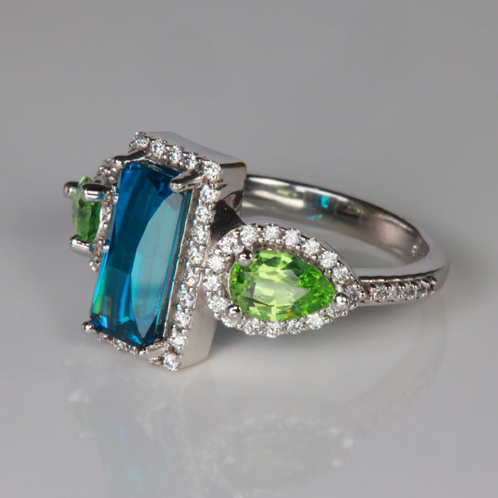 white gold ring with blue zircon and green garnet gems