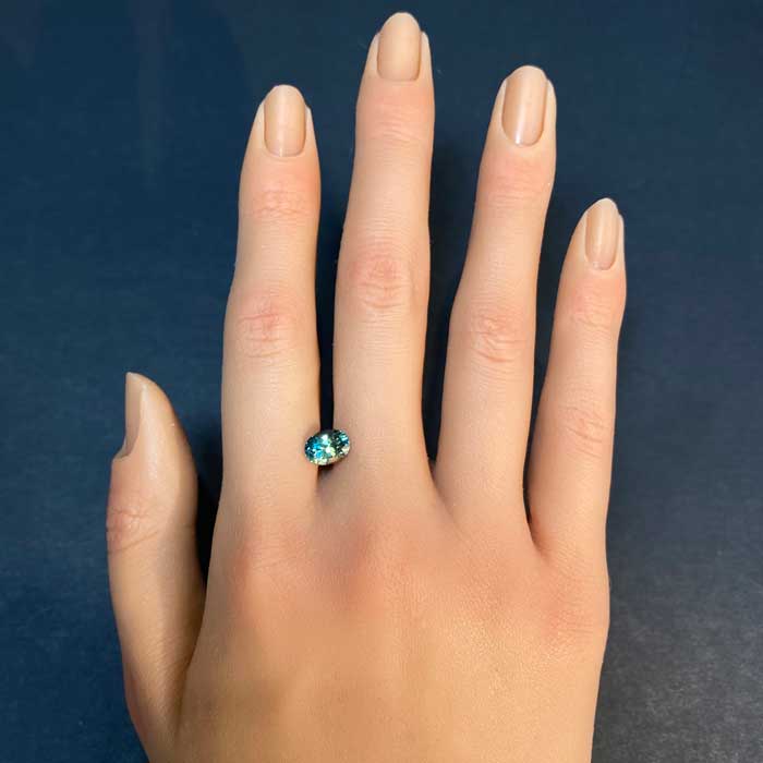 oval cut bicolor sapphire gemstone on hand