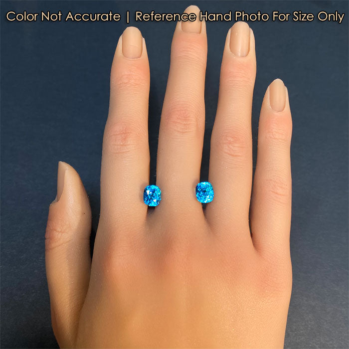 blue zircon gemstone pair on hand